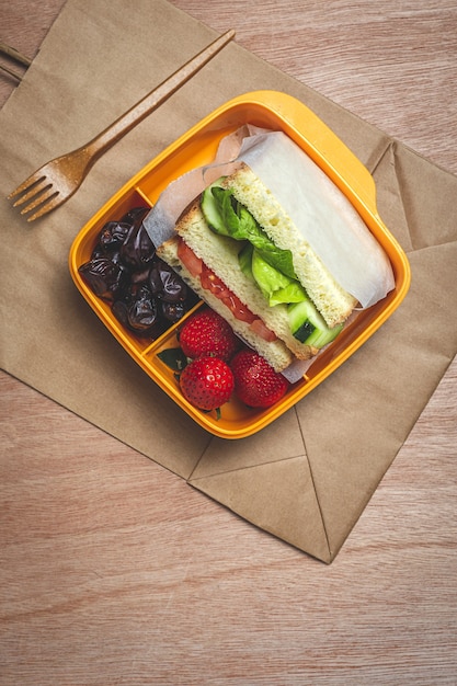 Vegan Sandwich in plastic container on wooden table. Healthy food concept