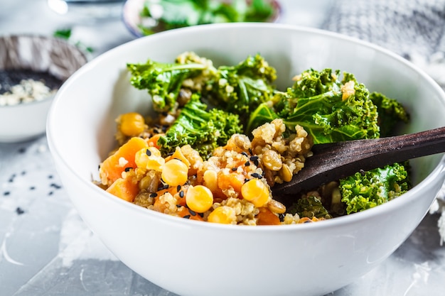 Vegan stew with chickpeas, sweet potato and kale in white bowl.