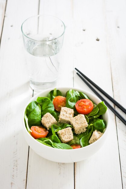 Photo vegan tofu salad with tomatoes and lamb's lettuce on white wooden table