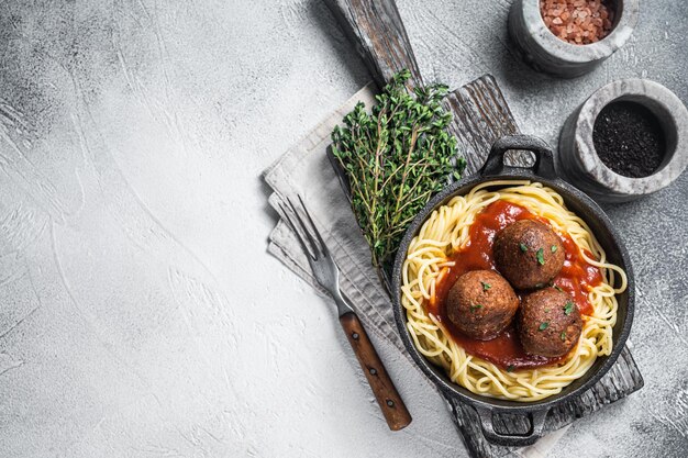 Pasta vegana al pomodoro con polpette vegetali in padella. sfondo bianco. vista dall'alto. copia spazio.