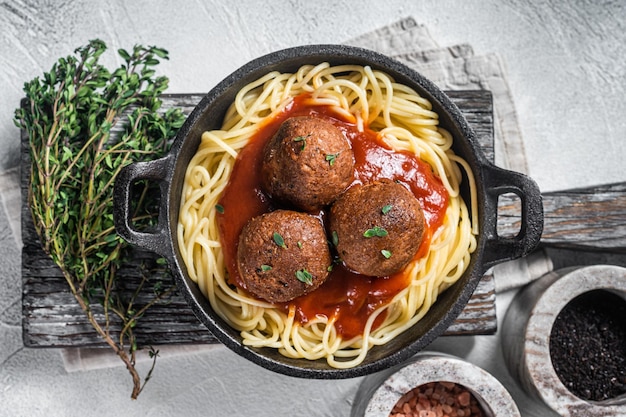 Pasta vegana al pomodoro con polpette a base vegetale in padella sfondo bianco vista dall'alto