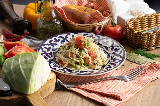 Vegan vegetable salad of cabbage, cucumber and tomatoes seasoned with oil in a plate with a traditional Uzbek 