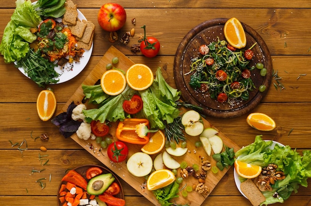 Vegan and vegetarian food. Variety of cut fruits and vegetables on wooden table, top view, flat lay, objects