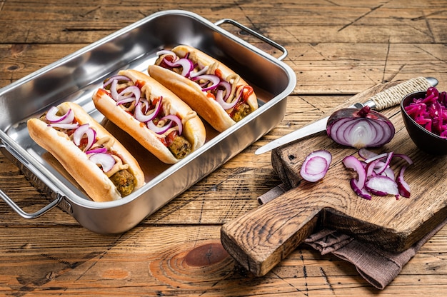 Vegan Vegetarian hot-dogs with onion and meatless sausage. Wooden background. Top view.