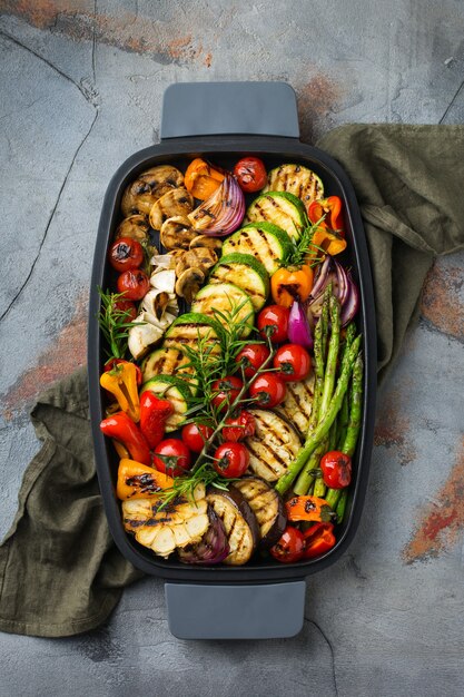 Vegan, vegetarian, seasonal, summer eating concept. Grilled vegetables in a pan on a dark black table. Top view flat lay background