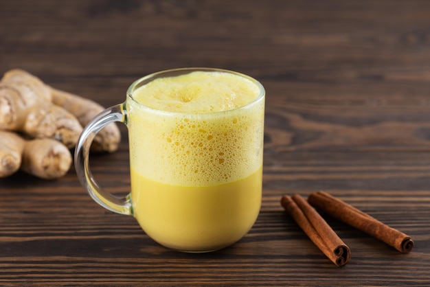 Vegan whipped turmeric golden latte from almond milk ginger turmeric and cinnamon on wooden table