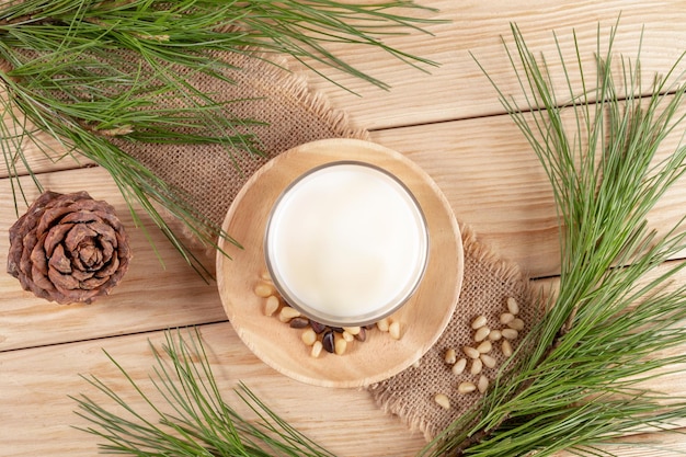 Veganist drink cedermelk in glas noten takken op jute servet op houten tafel Top view