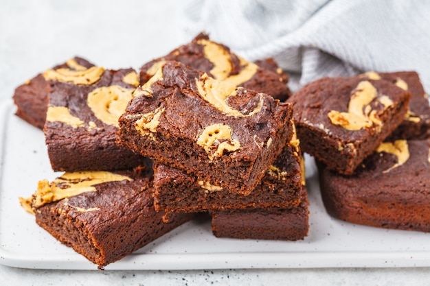 Veganistbrownie met pindakaas op witte achtergrond.