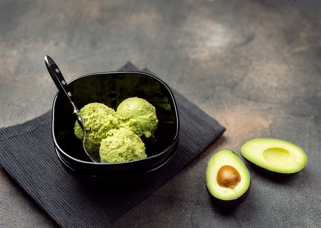 Foto veganistisch avocado-ijs in zwarte kom