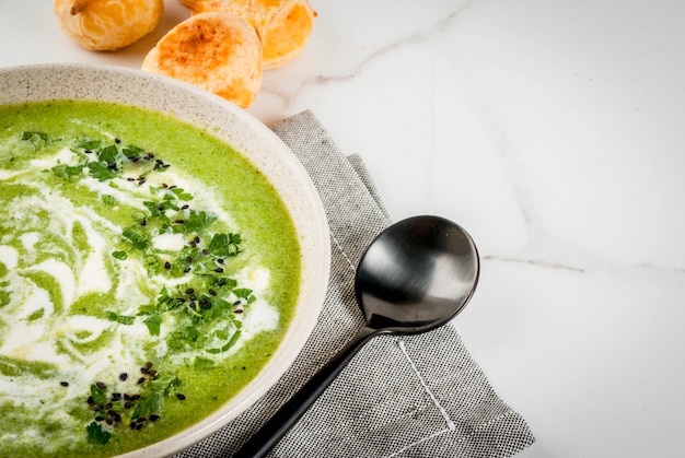 Veganistisch dieetvoedsel. Broccolisroomsoep, met kaasbroodjes, greens, op een witte marmeren tafel. Kopieer ruimte