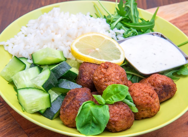 Veganistisch gerecht met soja gehaktballetjes, komkommer, rijst en yoghurtsaus