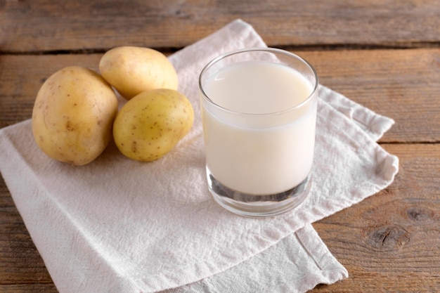 Veganistische aardappelmelk en aardappel op bruine houten achtergrond close-up plantaardige alternatieve melk