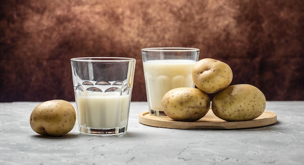 Veganistische aardappelmelk in glas en rauwe aardappel alternatief plantaardig melk superfood concept gezond schoon eten veganistisch of glutenvrij dieet banner menu recept plaats voor tekst