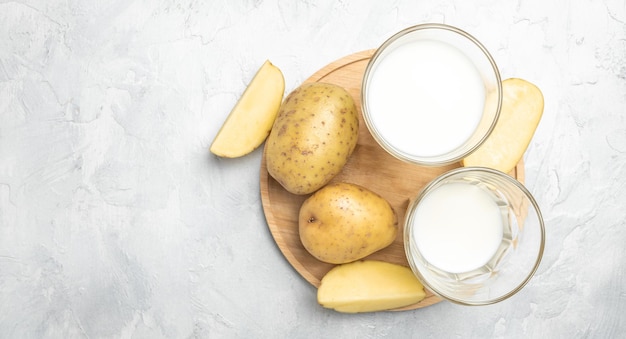 Veganistische aardappelmelk in glas en rauwe aardappel Alternatief plantaardig melk superfood concept Gezond schoon eten Veganistisch of glutenvrij dieet bovenaanzicht