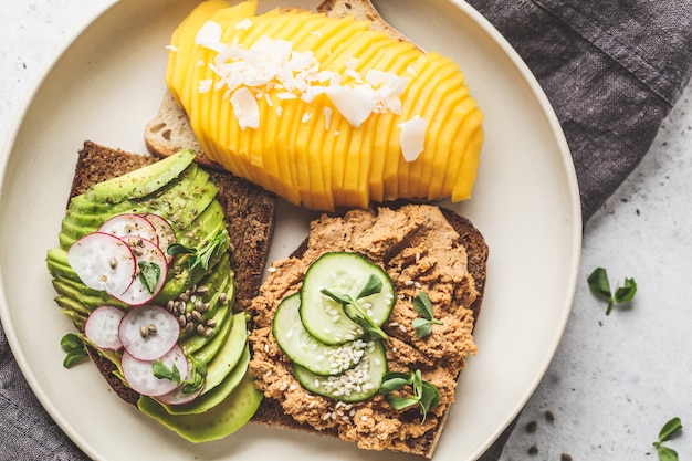 Foto veganistische broodjes met mango, avocado en tofu pate op een witte plaat.