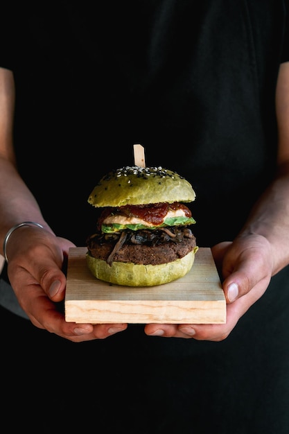 Veganistische burger met champignons, avocado, salsa en kaas, zwarte bodem. Gezonde maaltijd.