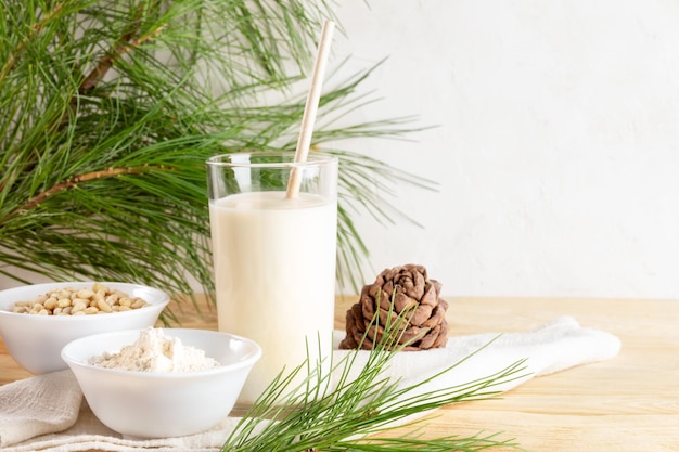 Veganistische cedermelk in glas en ingrediënten voor het koken van meel en noten op houten tafel Kopieer de ruimte