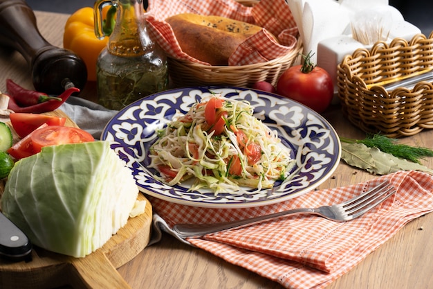 Veganistische groentesalade van kool, komkommer en tomaten gekruid met olie in een bord met een traditionele Oezbeeks