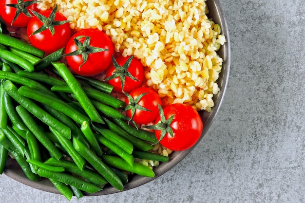 Veganistische kom met bulgur, kerstomaatjes en sperziebonen. Gezond eten in een kom. Veganistische lunchschaal.