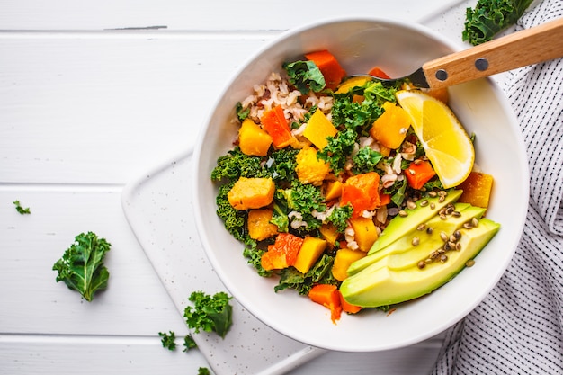 Foto veganistische salade met rijst, boerenkool, gebakken pompoen, wortelen en avocado