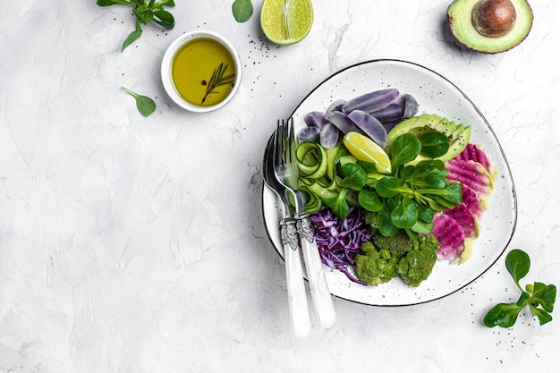 Veganistische salade met zoete aardappelen, broccoli, avocado, paarse kool, komkommer, watermeloen, radijs en amandelen