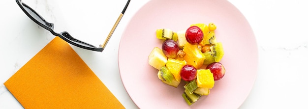 Veganistische salade van vers fruit op een roze bord gezonde voeding en detox