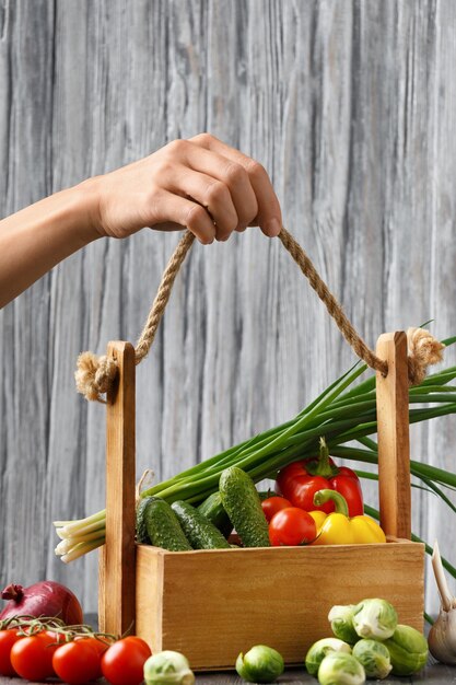 木製の背景に手で野菜のバスケット