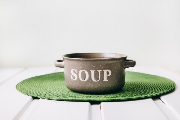 Vegetable broth in a kemamichesky plate on the background of a green napkin