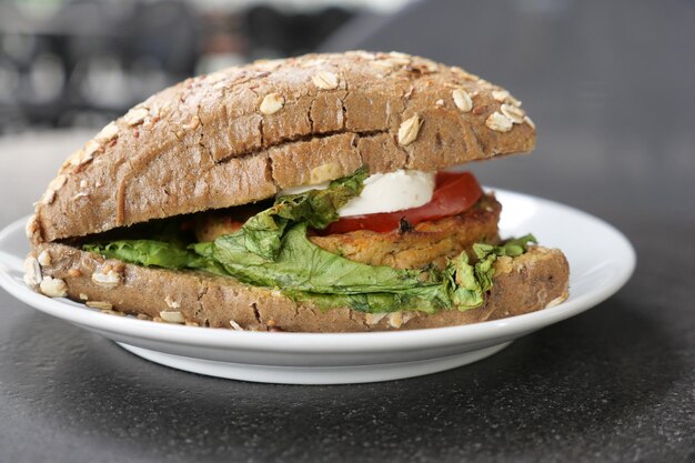 A vegetable burger with lettuce and tomato on a plate on table