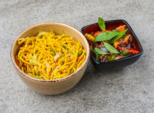 アジア料理の背景上面に分離された皿に盛り付けられたハニーチキンチリと野菜の焼きそば
