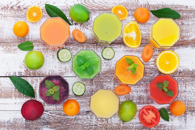 野菜と柑橘類のジュース。木製の机の上の野菜や果物の断片。珍しい上面図