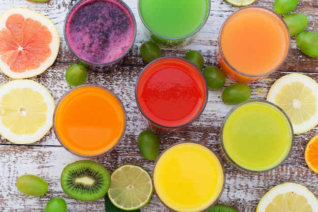 Vegetable and citrus juices Pieces of vegetables and fruits on wooden desk Unusual top view