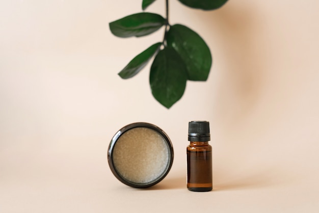 Vegetable cosmetics for body care in beauty salons. Bottle and jar with oils on a beige  wall with leaves of green zamiokulkas