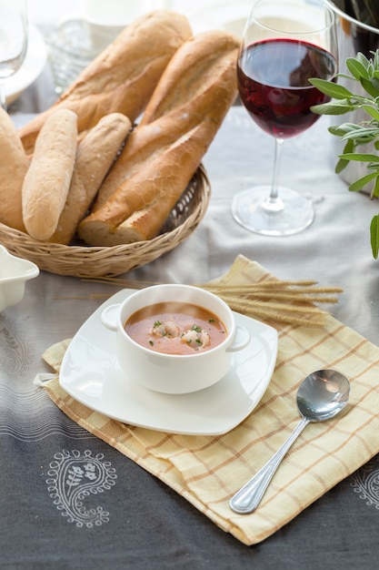 Vegetable cream soup with shrimps and croutons in white bowl close up