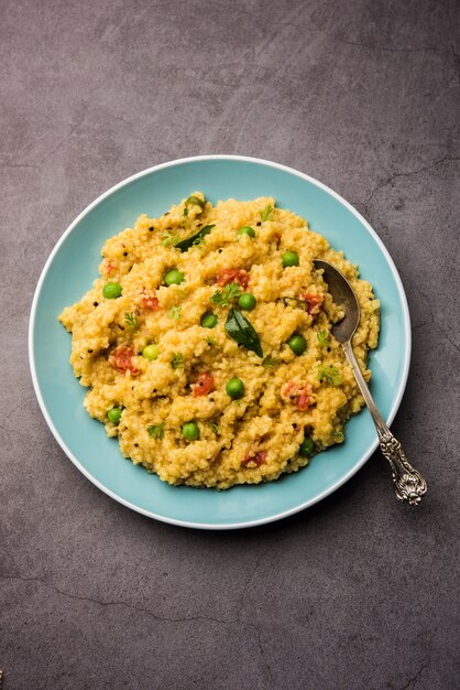 Vegetable Dalia or Daliya Khichadi or Broken Wheat Khichdi with tomato, green peas and chilli, served in a bowl or plate