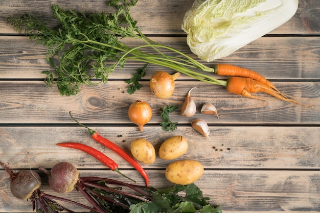 Vegetable food composition of onion cabbage beet chili pepper carrot potato and garlic on wooden table background