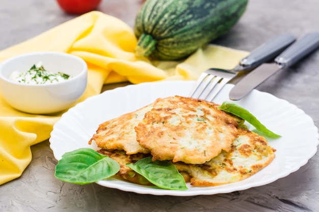 ズッキーニとバジルから揚げた野菜のフライは、プレートとテーブルの上のカトラリーの葉