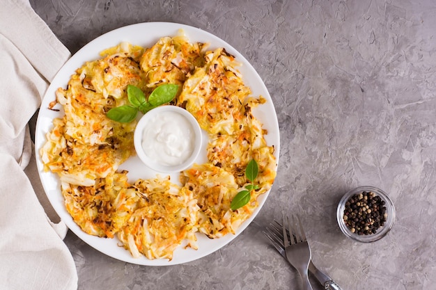 Vegetable fritters from cabbage and carrots and sauce on a plate Vegetarian food Top view