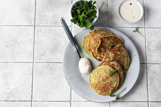 Vegetable fritters with herbs and dip grey tiled background Vegetarian broccoli or spinach pancakes