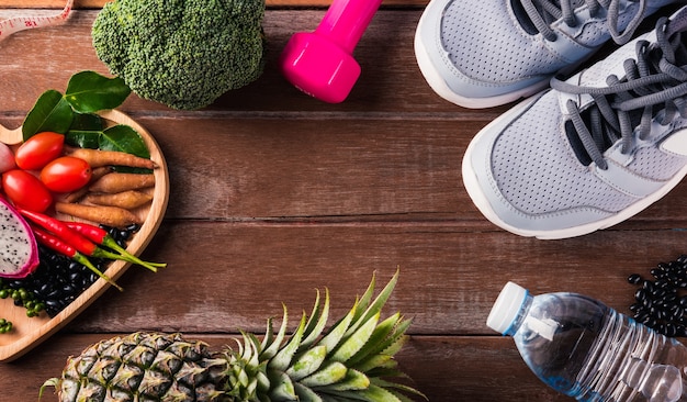 Photo vegetable in heart plate and sports shoes, dumbbell and water