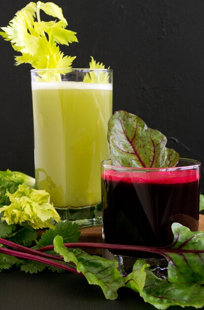 Vegetable juice in glass cups on a black background. Beets, celery, carrots.