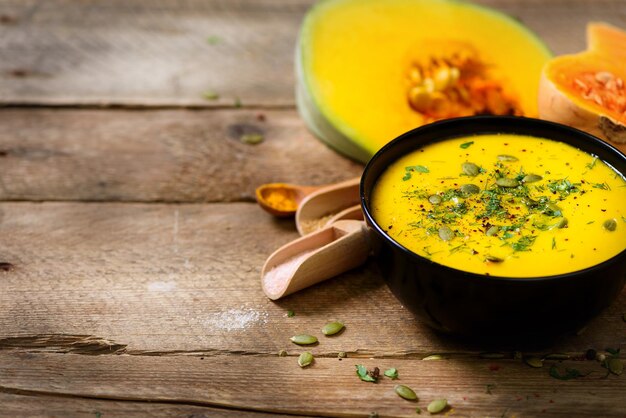 Vegetable and lentils creamy soup cut pumpkin seeds parsley on rustic wooden background Top view copy space