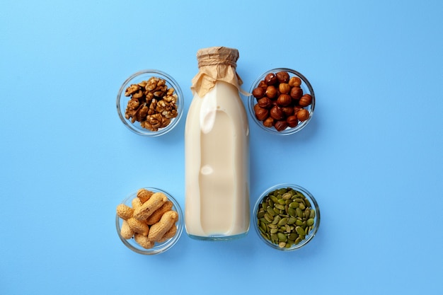 Concetto di latte vegetale con bottiglia per il latte e ciotole con vista dall'alto di cereali e noci