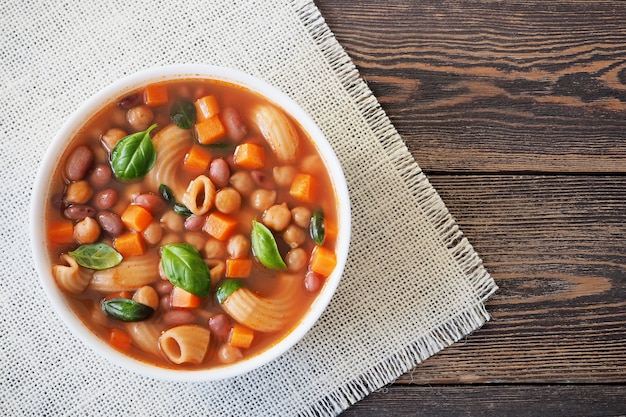 写真 リネンナプキン上面図の白いカップにパスタと野菜のミネストローネスープ