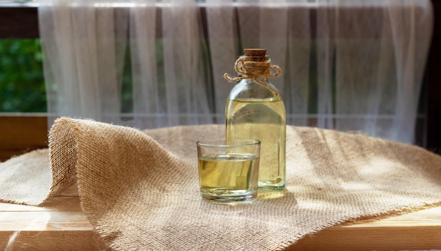 Vegetable oil in a bottle glass on burlap canvas fabric background