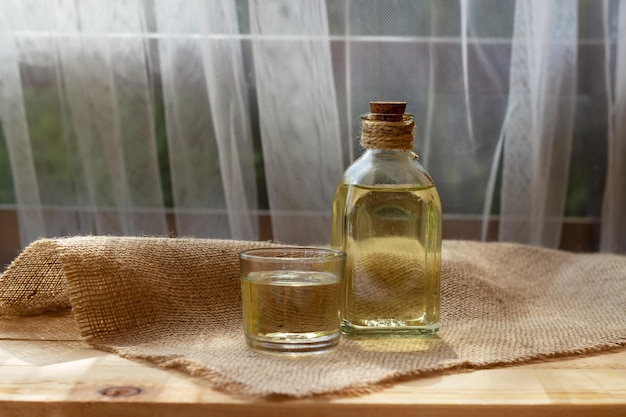 Vegetable oil in a bottle glass on burlap canvas fabric background