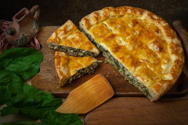 Vegetable pie homemade baking with spinach and onions on a dark wooden background