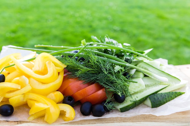 写真 明るい緑の芝生を背景に木製の皿に野菜プレート 健康食品のコンセプト 水平写真