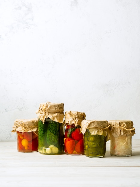 Vegetable preserves in glass jars on white background. Vertical image with copy space