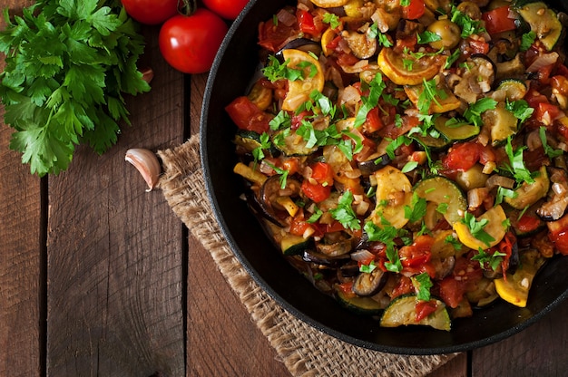 Vegetable Ratatouille in frying pan on a wooden table